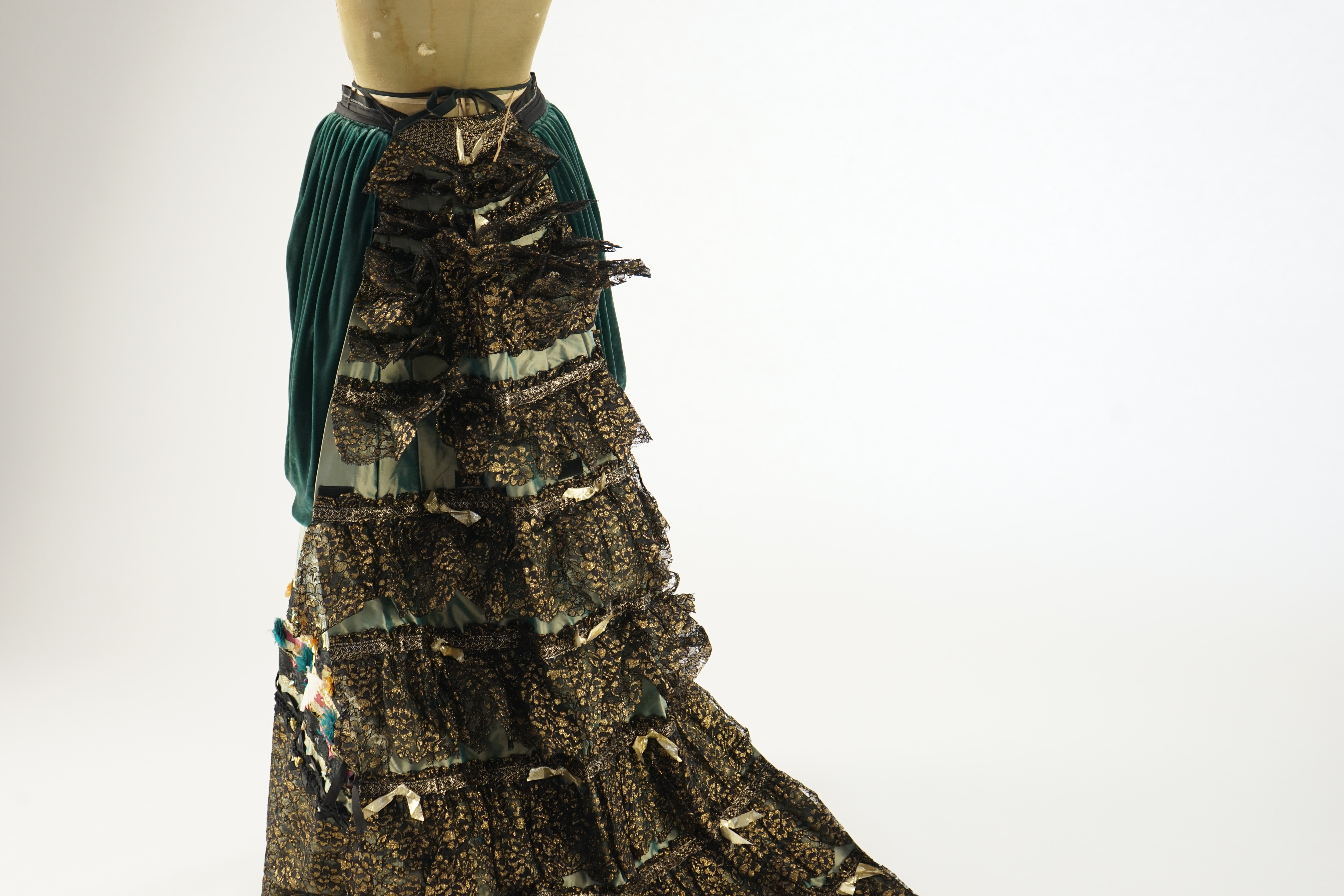 An Edwardian style lady's green taffeta skirt decorated with beaded, sequinned, ribboned border and swags of silk velvet, together with matching train layered with frilled black and gold lace, appliquéd with gold bows